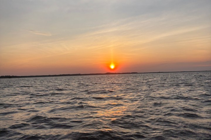 Sunset over a calm sea with a clear sky.